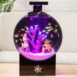 Rond aquarium op zwarte basis met paarse LED-verlichting, decoratie (koraal, zeemeermin en ananashuis) en vissen ter illustratie in een woonkameropstelling.